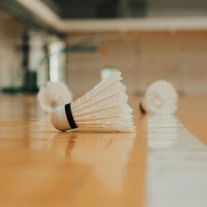 Ground level of similar plastic shuttlecocks reflecting on bright shiny floor with marking line